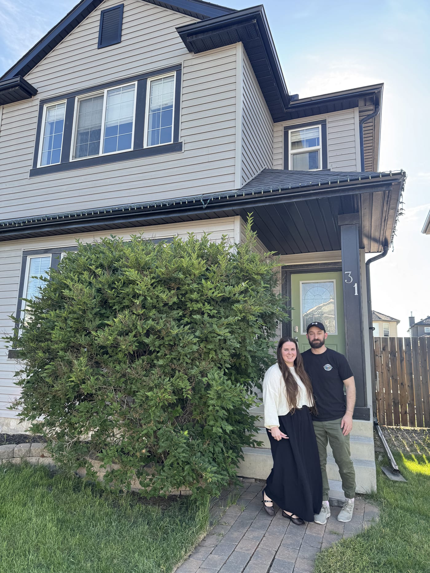 Clients smiling in front of their newly purchased home in Calgary